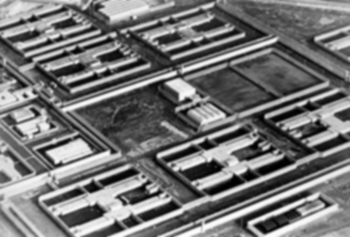 Aerial black and white photograph of a large rectangular prison complex with multiple wings and courtyards