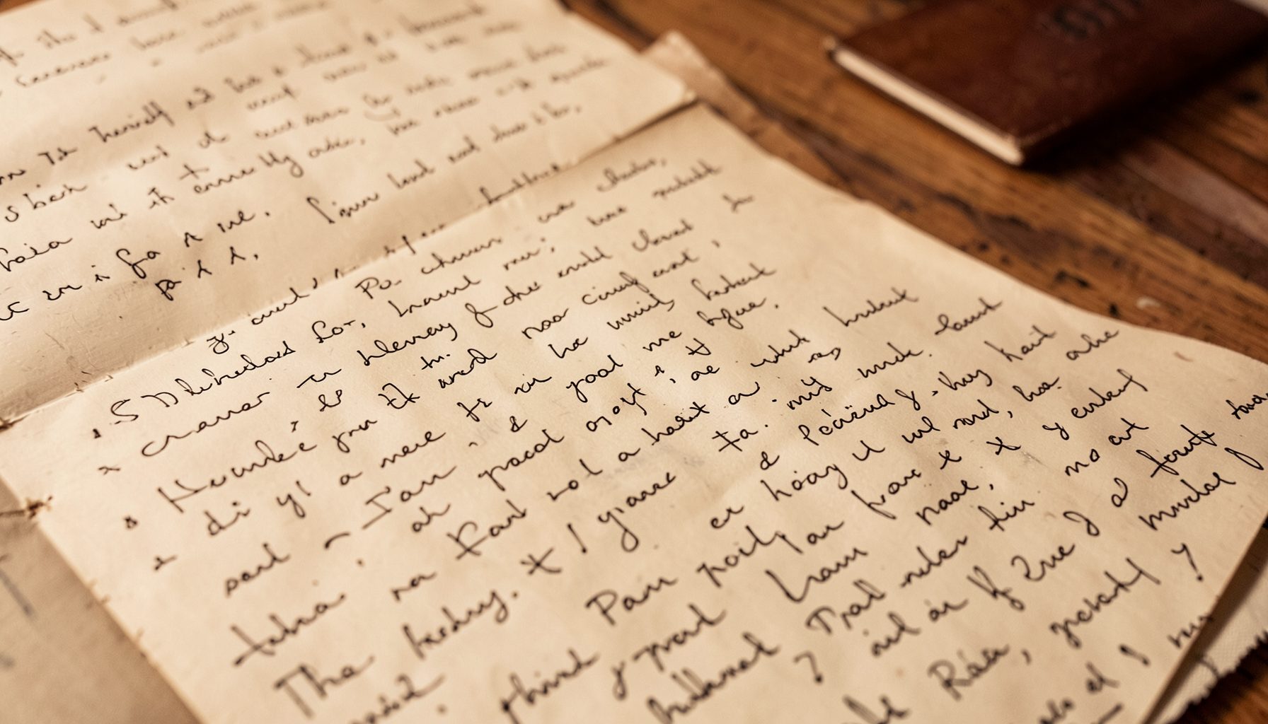 Warm-toned photograph of handwritten pages on a wooden surface, suggesting personal writings and reflection